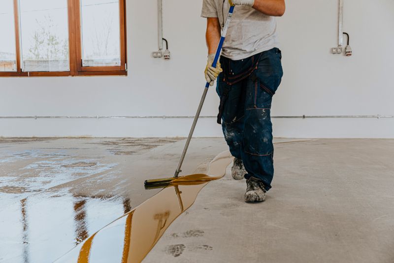 worker installing epoxy coating on garage flooring