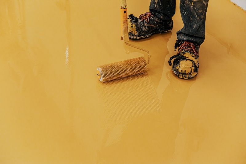worker smoothing epoxy coating with a roller